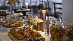 Una mesa de bufé con diversos alimentos, incluyendo pasteles, un pastel y frascos de pepinillos.