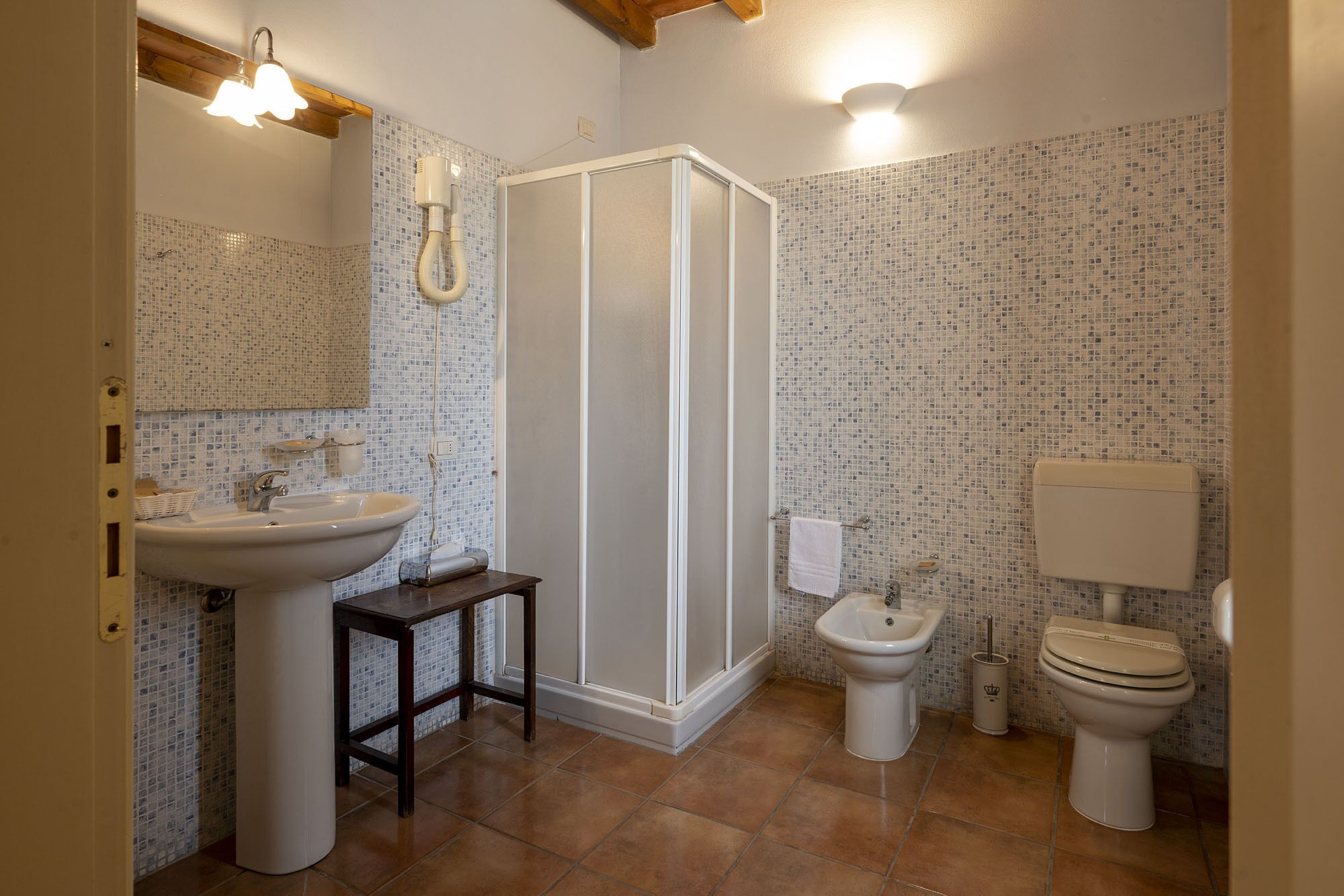 Un baño con ducha, lavamanos, inodoro y espejo.