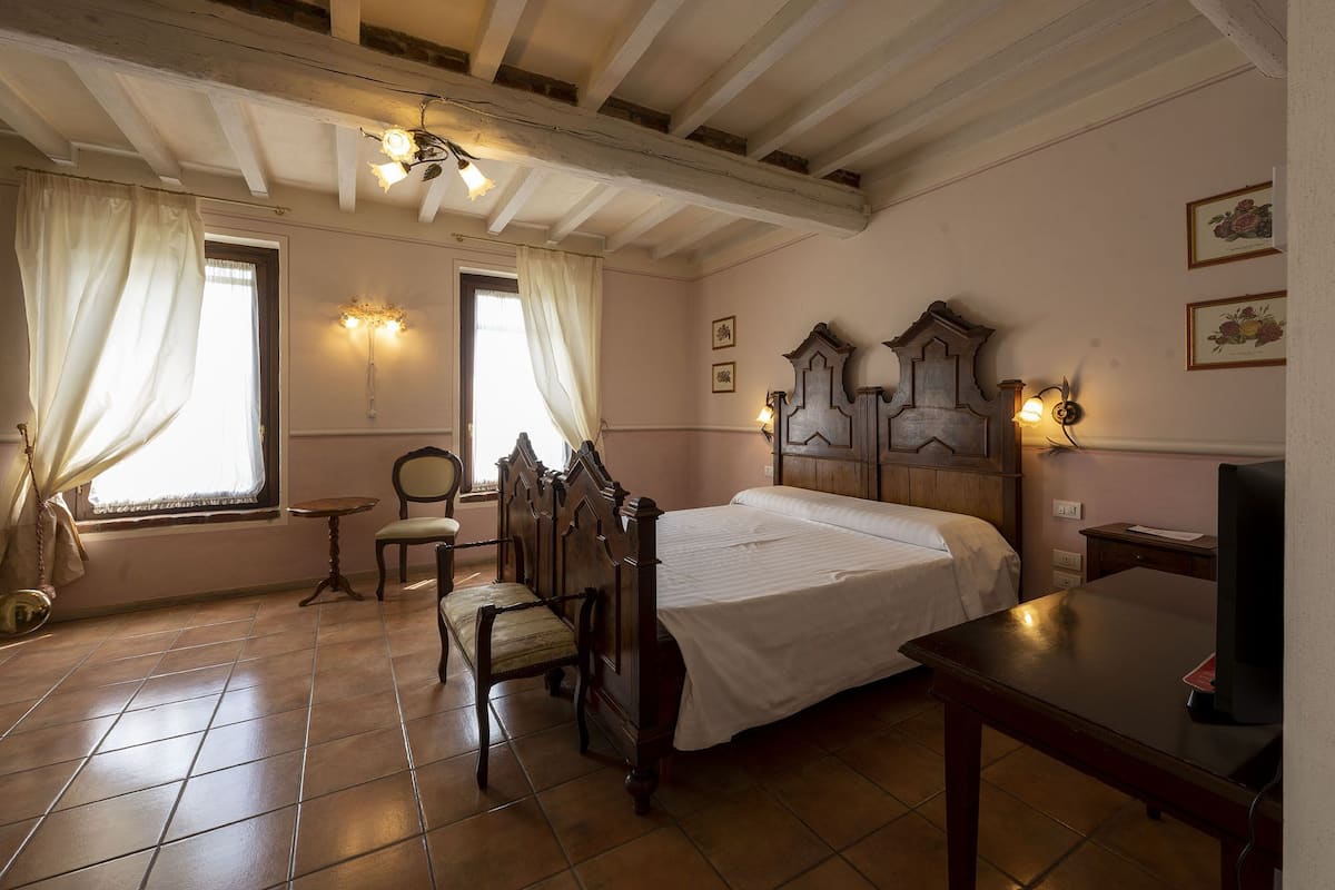 A traditional room with a wooden bed, a chair, a small table, and a television.