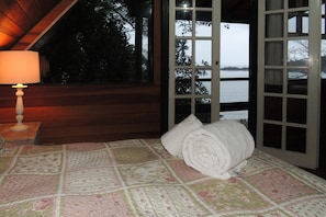 A bedroom with a bed, a rolled-up towel, and a lamp.