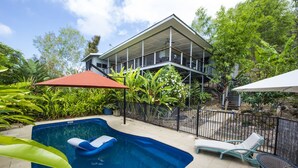A swimming pool with lounge chairs and a covered patio area.
