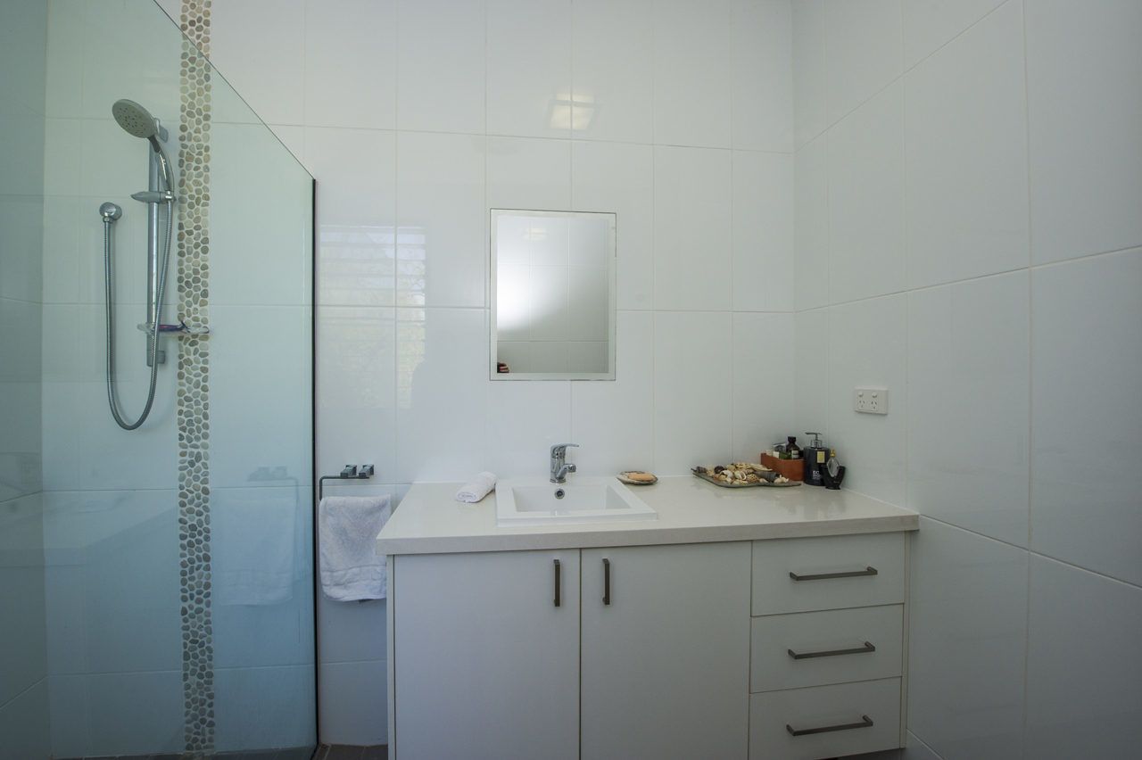 Un bany modern amb una dutxa de vidre, un lavabo blanc i un mirall a sobre.