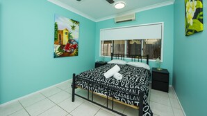 A bedroom with a bed, a ceiling fan, a window with blinds, and a painting on the wall. - Azure on Geoffrey Bay (Arcadia)