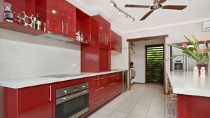 Una cocina moderna con armarios rojos, un horno de acero inoxidable y un ventilador de techo.