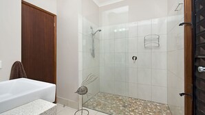 Un baño moderno con cabina de ducha de vidrio, una bañera blanca y suelo de ducha con mosaicos.