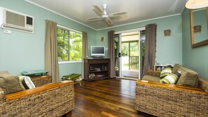 Ein Wohnzimmer mit Rattan-Sofas, einem Fernseher und einem Deckenventilator.