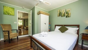 Ein Hotelzimmer mit einem Bett, einem Sessel, einem Deckenventilator und Bildern an den Wänden.