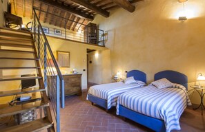 Ein Schlafzimmer mit zwei Betten, einer Holztreppe und einem Balkon.