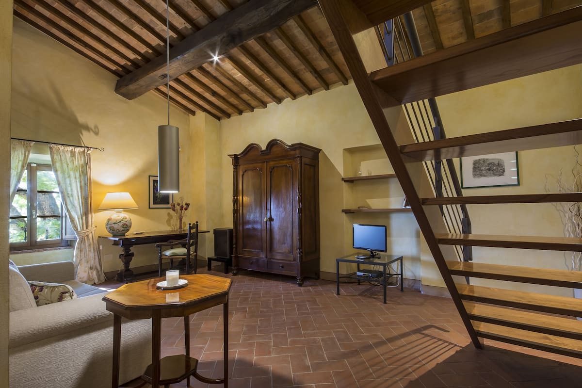 Una habitación acogedora con techo de madera, un armario grande, un televisor y una mesa con una vela.