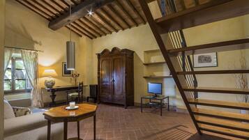 Una habitación acogedora con techo de madera, un armario grande, un televisor y una mesa con una vela.