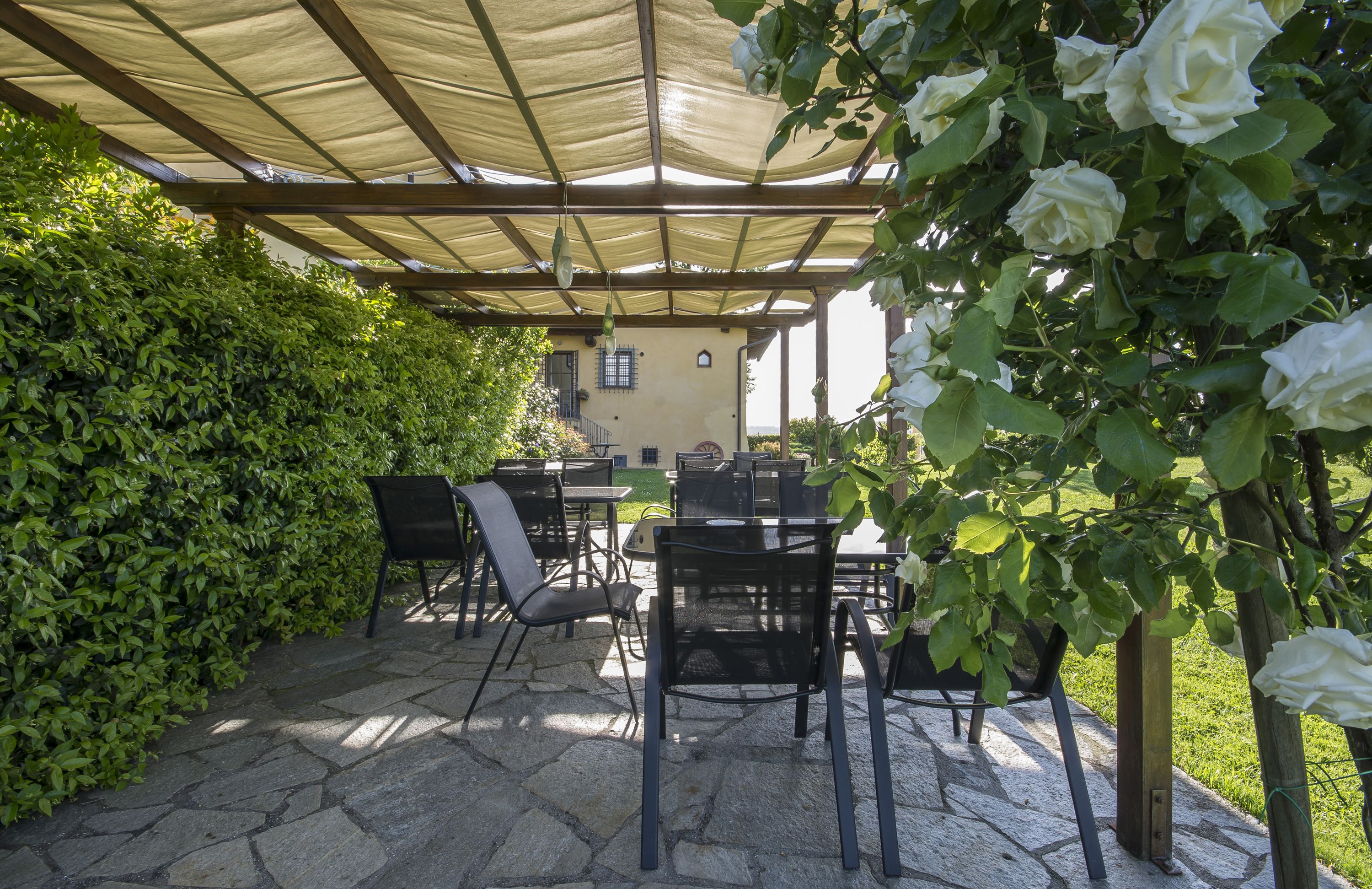 An outdoor patio with stone flooring, black metal chairs, and a table.