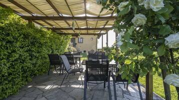 An outdoor patio with stone flooring, black metal chairs, and a table.