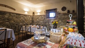 A dining area with stone walls, a stone fireplace, and a breakfast buffet with fruits and pastries. - Il Nido di Gabbiano (Scarperia e San Piero)