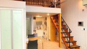 A modern apartment with a dining area, kitchen, and a staircase leading to an upper floor. - Travel House (Seoul)