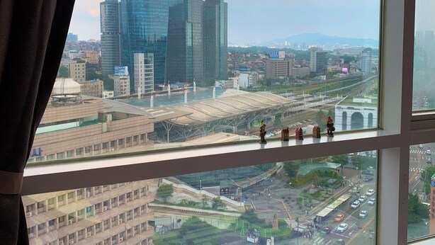 A view from a window overlooking a cityscape with modern buildings, a bridge, and a railway station. - Travel House (Seoul)