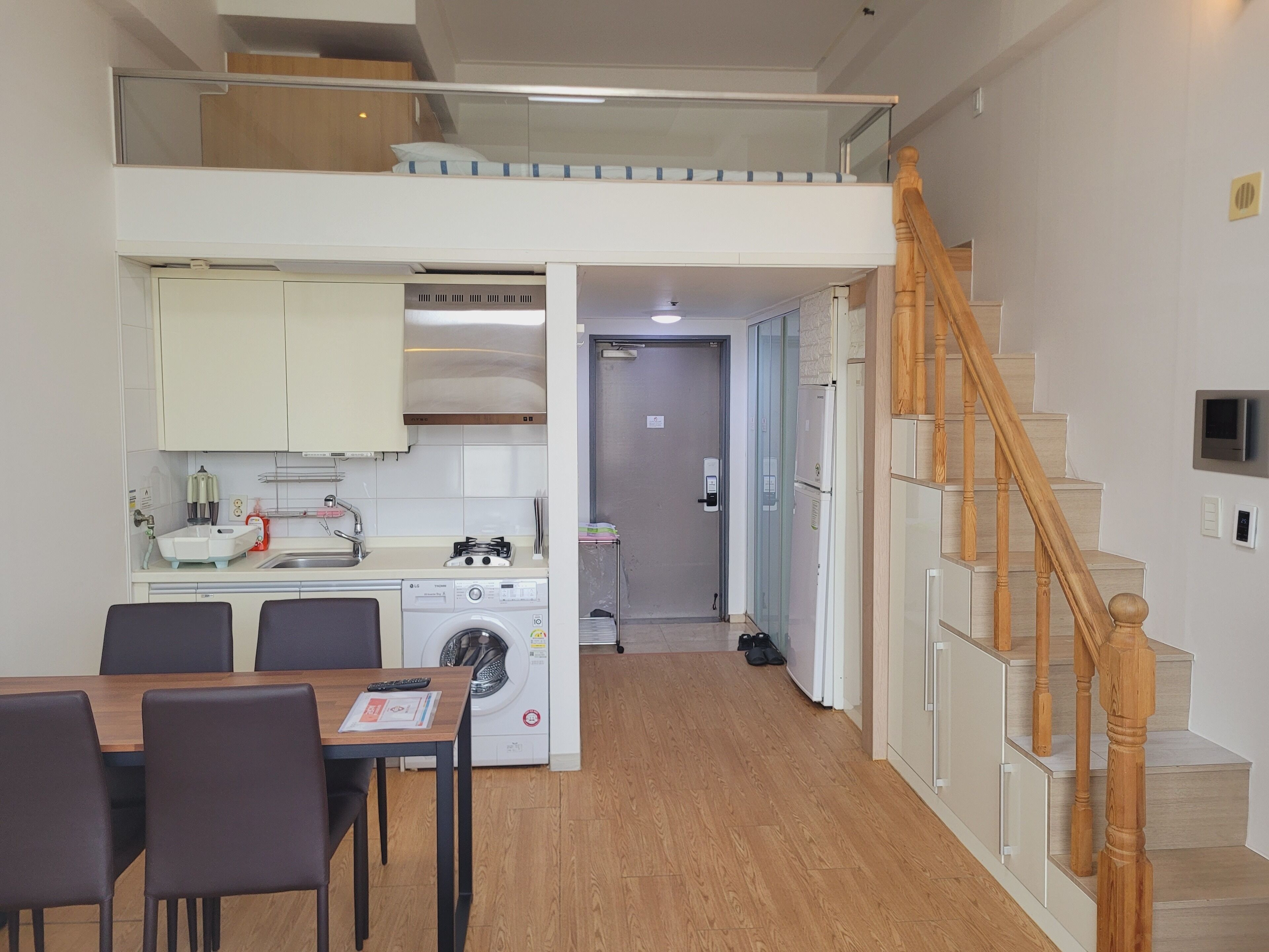 A modern apartment with a kitchen, dining area, and a staircase.