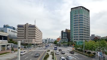 A busy urban street with modern buildings, including a prominent high-rise with a curved top.