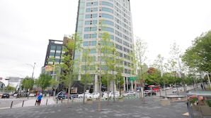 A modern high-rise building with a curved facade, surrounded by trees and a busy street with cars and a bus. - Travel House (Seoul)