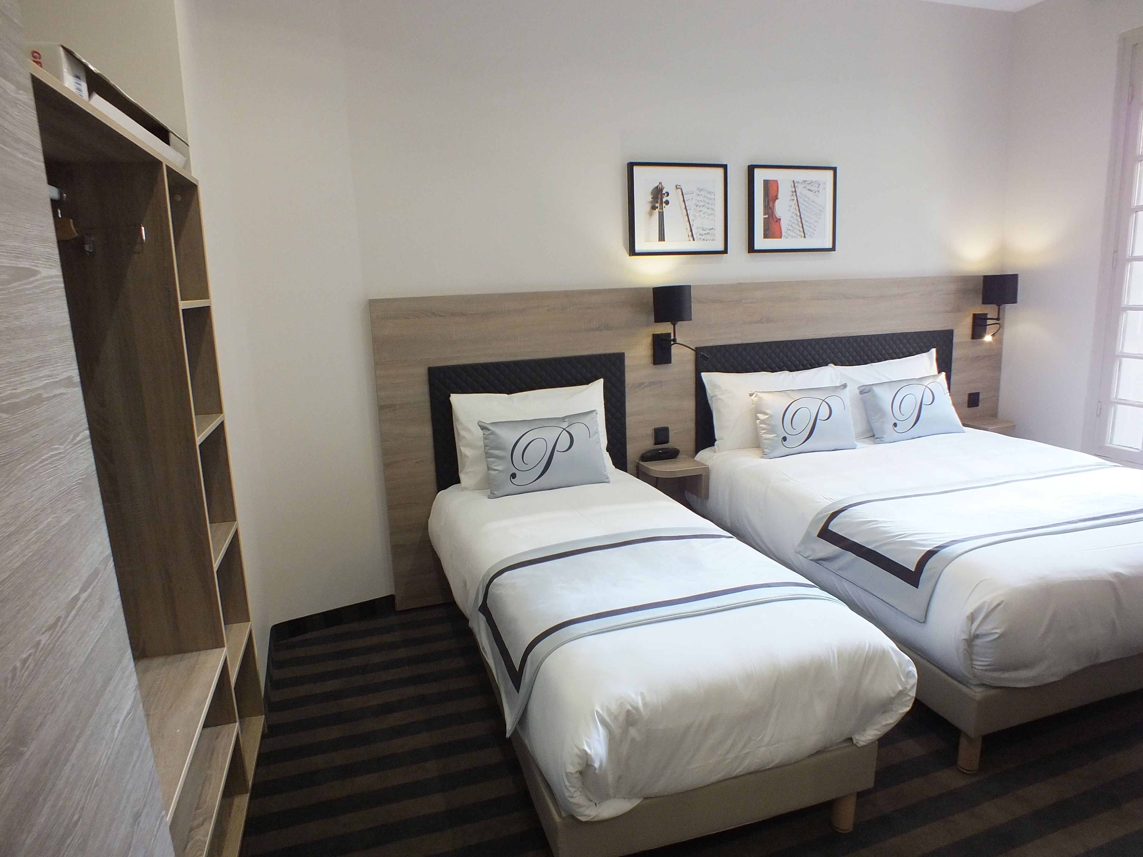 Una habitación de hotel con dos camas, un armario y cuadros en la pared.