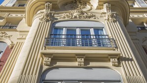 Een gebouw met klassieke architectuur, bestaande uit versierde zuilen, grote ramen en een balkon.