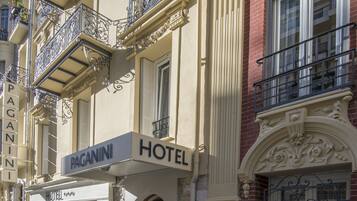 Een hotel met een bord waarop "PAGANINI HOTEL" staat en een "HOTEL" bord boven de ingang.