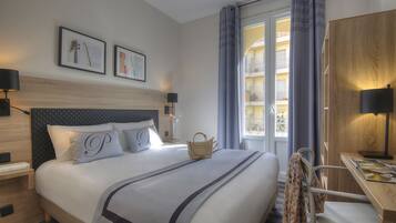 Una habitació d'hotel amb un llit gran, un escriptori i vista de l'interior de l'edifici.