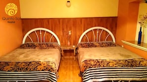 A hotel room with two beds, wooden headboards, a small table with a vase, and a mirror above the table.