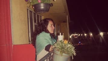 Un balcón con plantas colgantes y una maceta en el suelo.