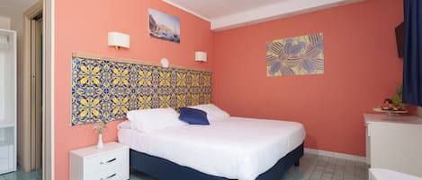 Un dormitorio con cama, mesita de noche, escritorio y silla.