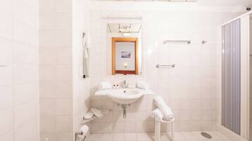 A modern bathroom with a white sink, mirror, and shower.