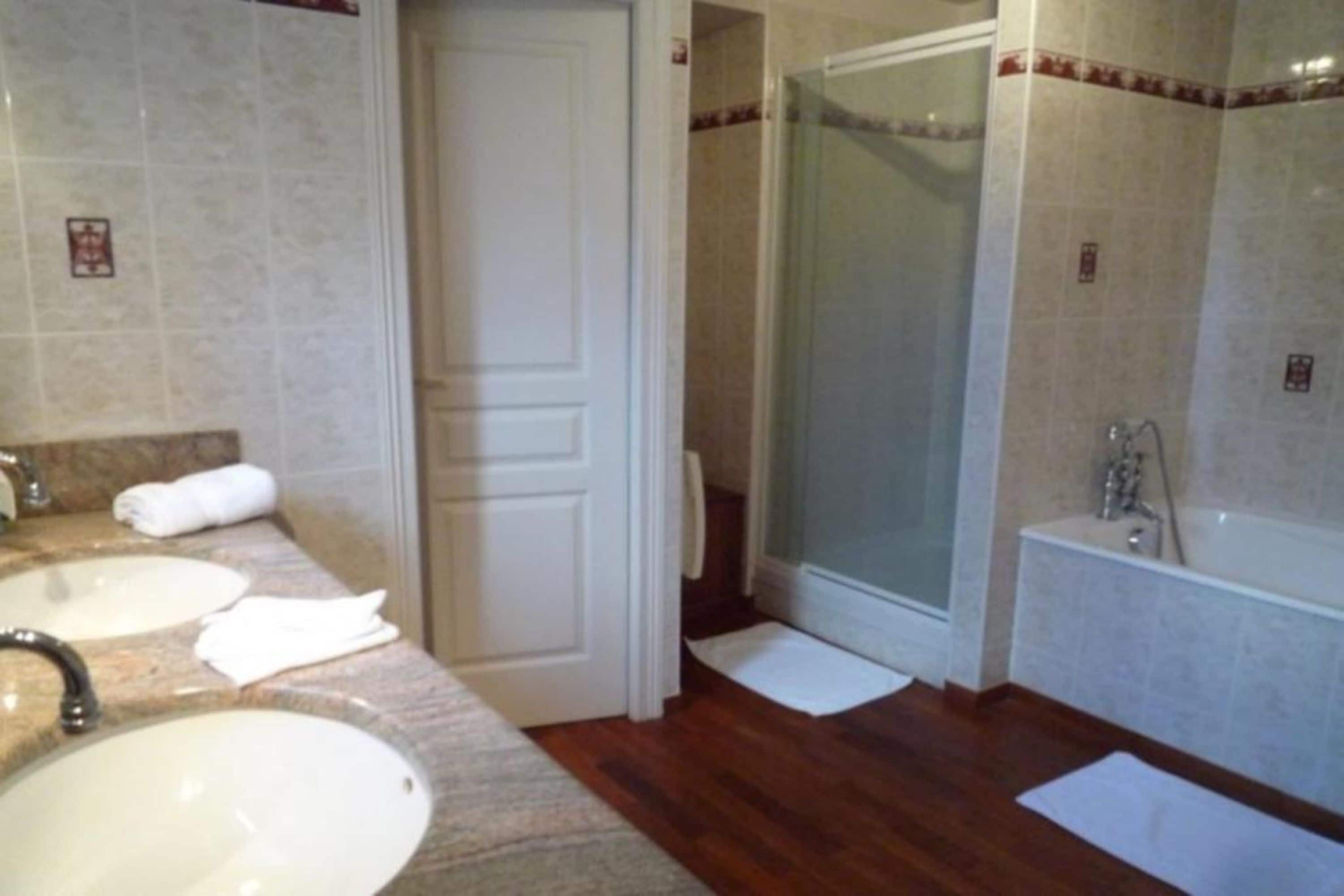 A bathroom with two sinks, a shower, and a bathtub.