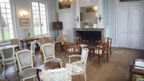 A room with a fireplace, multiple chairs, and a large window. - Château de Béhen (Behen)