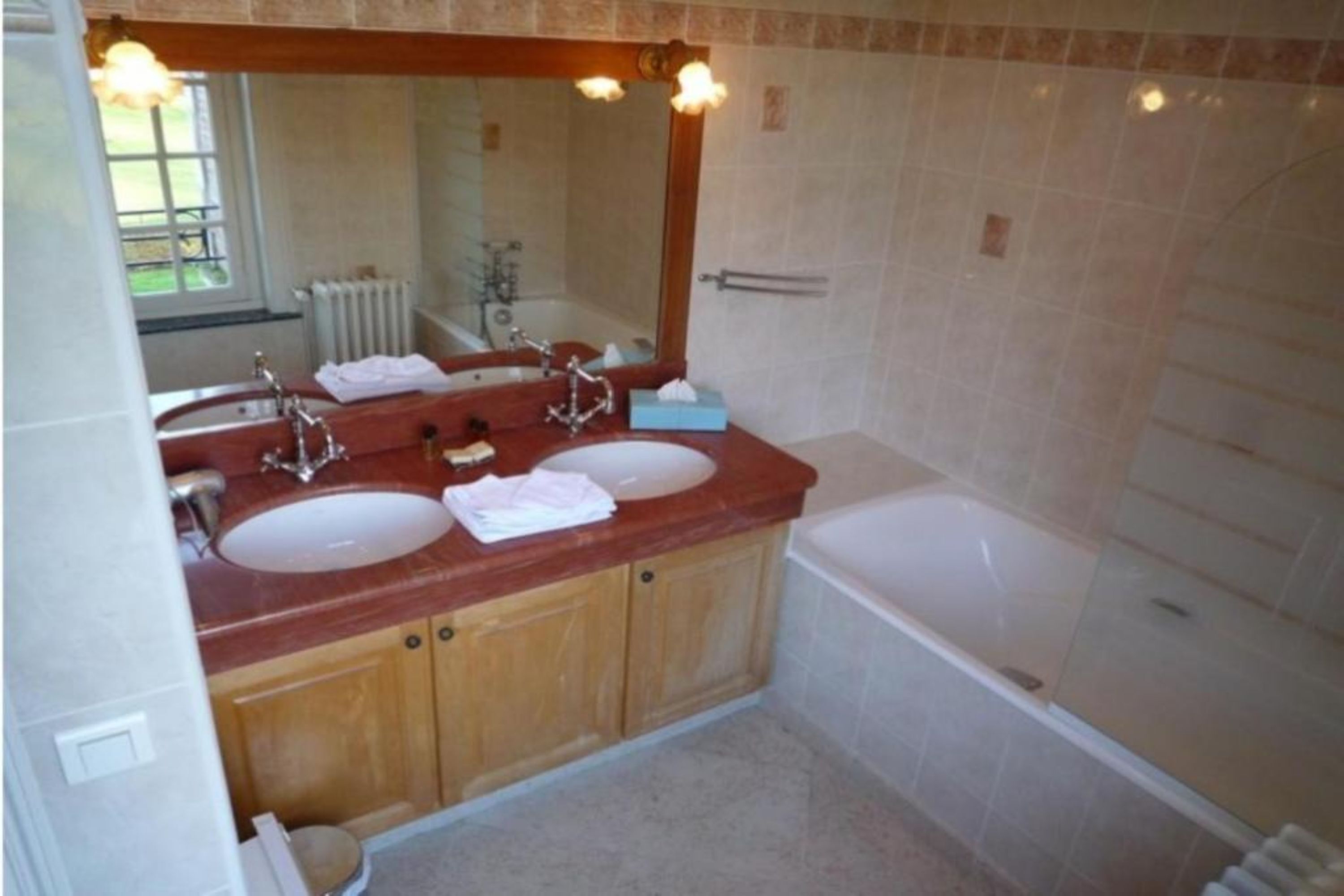 A bathroom with two sinks, a large mirror, and a bathtub.