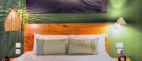 Ein Schlafzimmer mit Bett, Kissen, einer Hängelampe, einer Wandlampe und einem Gemälde, das einen Surfer zeigt.