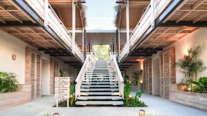 A staircase leading to a building with wooden railings and a sign indicating room types and numbers. - The Gilded Iguana Surf Hotel (Nosara)