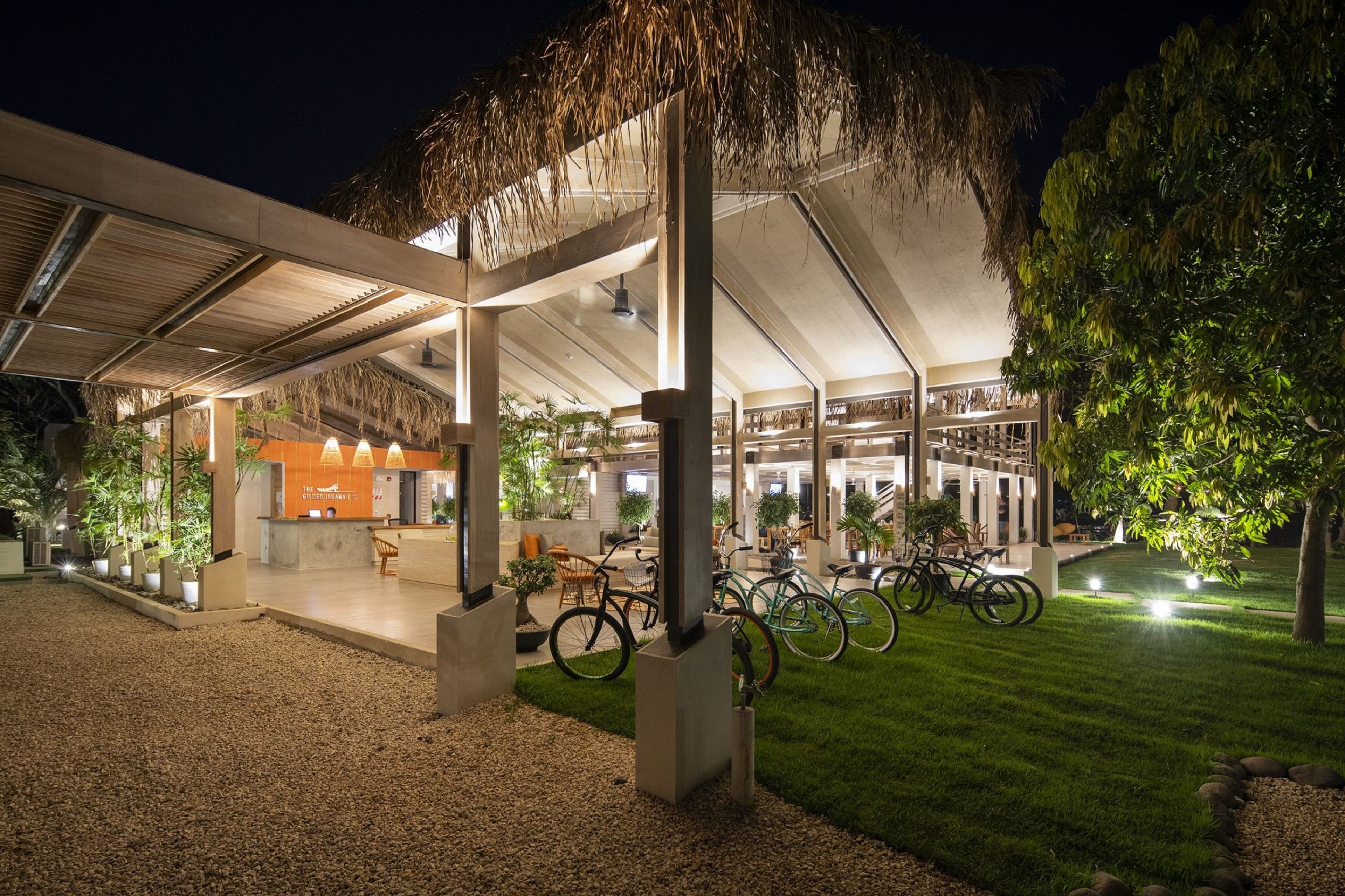Een modern gebouw met een overdekt terras, fietsen en potplanten.