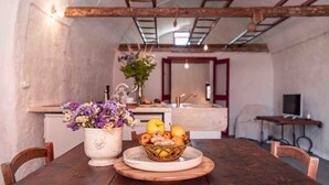 Une table à manger avec un panier de fruits et un vase de fleurs.