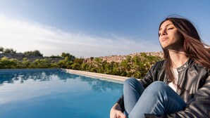 Une personne assise au bord d’une piscine, d’où elle a une vue dégagée sur le paysage environnant.