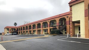 A motel with a red-tiled roof, multiple balconies, and a parking lot.