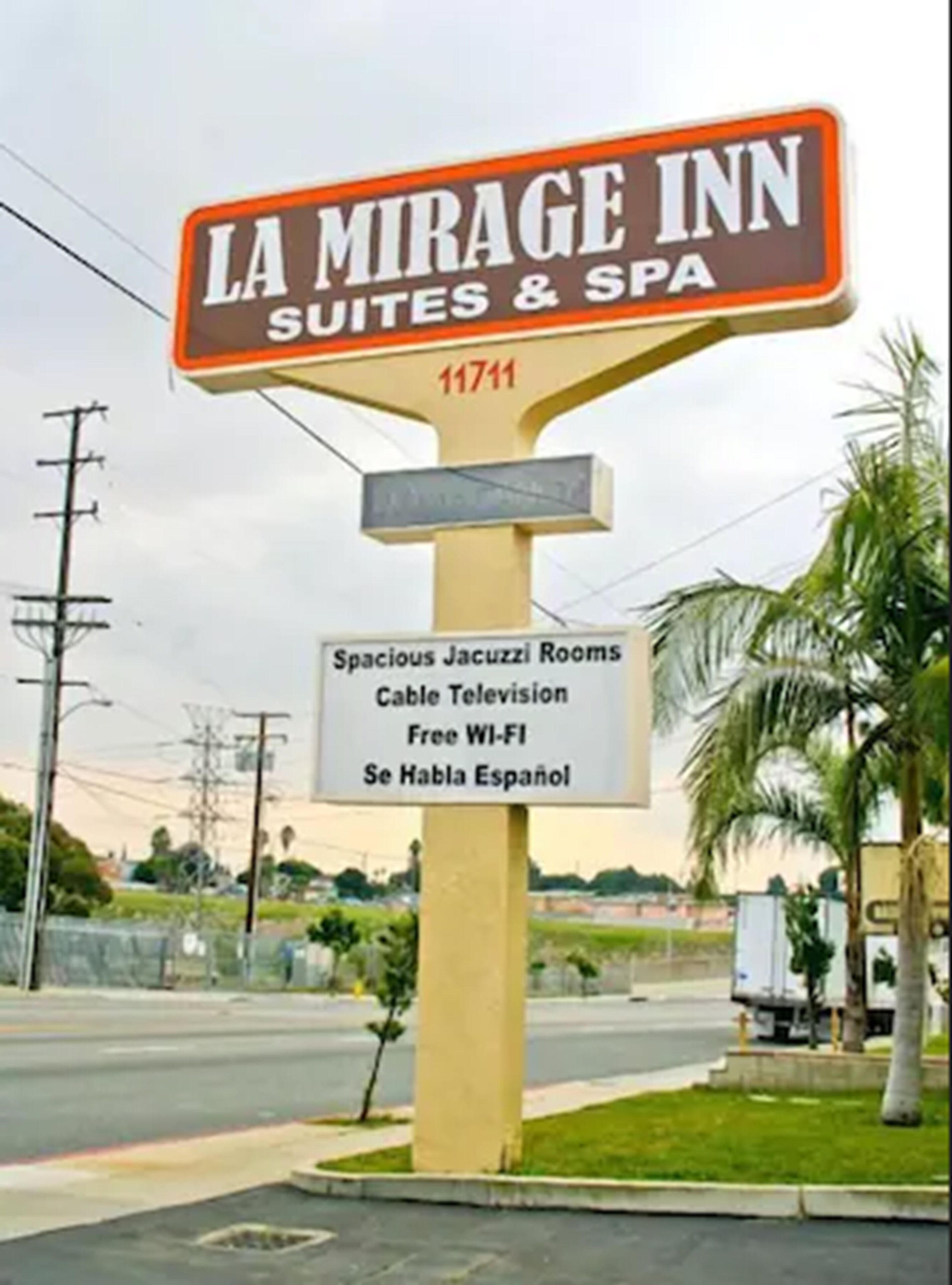 Placa do La Mirage Inn Suites & Spa, listando comodidades como quartos espaçosos com hidromassagem, televisão a cabo, Wi-Fi gratuito e equipe que fala espanhol.