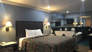 A hotel room with a large bed, a desk, a chair, a mirror, and a bathroom area.