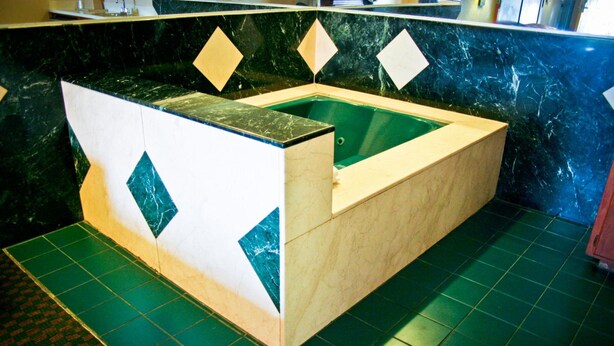 A spa area with a wooden tub and a green floor.