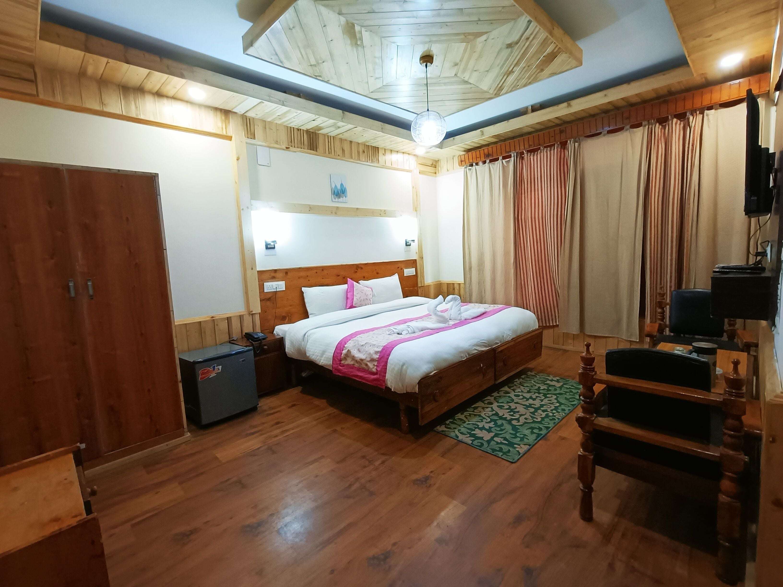 A wooden-paneled bedroom with a bed, bedside table, and a desk with a chair.