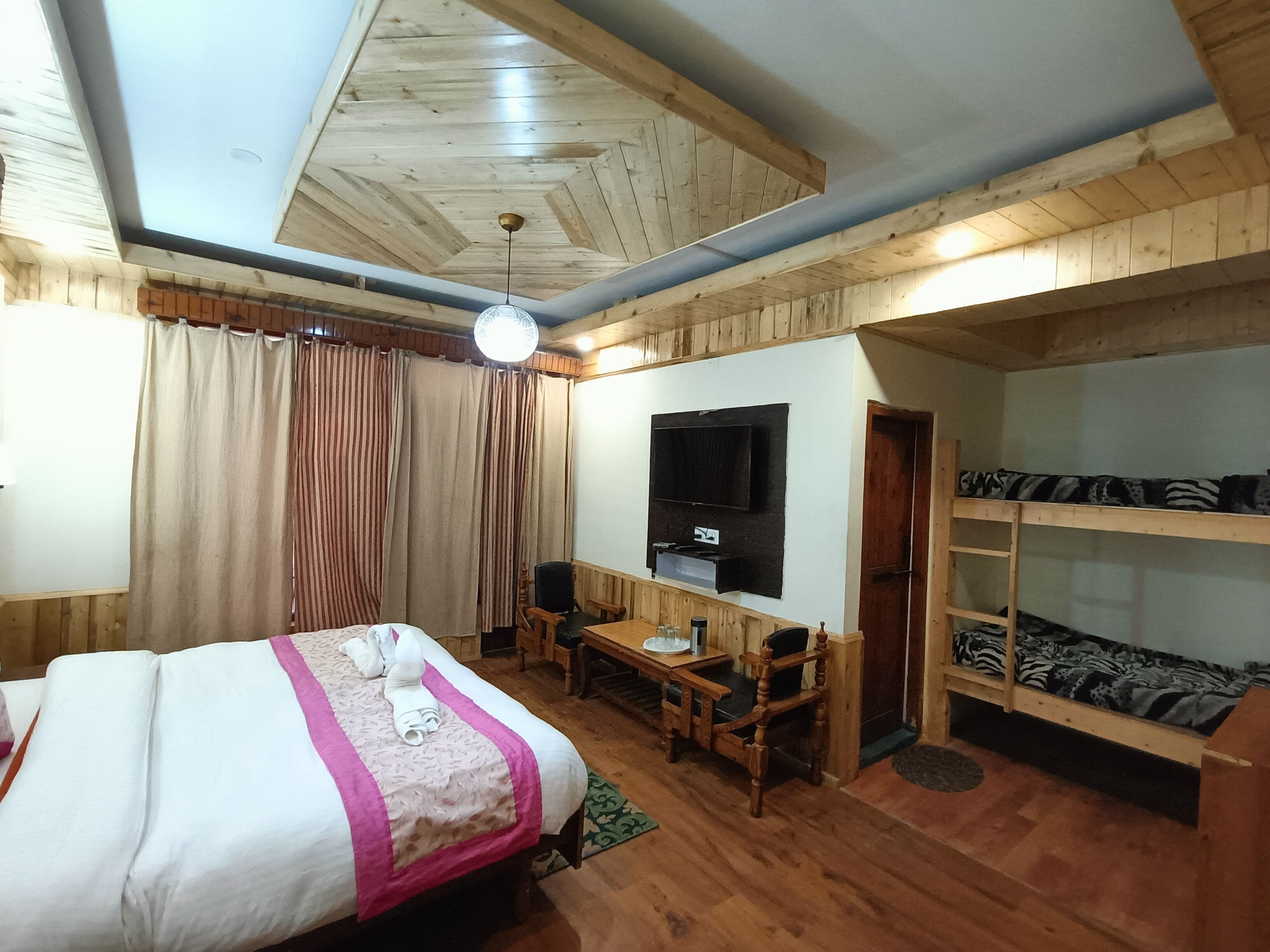 Una habitación con una cama, un escritorio, una silla, un televisor y literas.