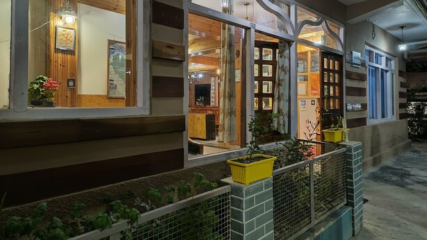 A building with large windows, a wooden facade, and a balcony with plants. - CS Shhandella Hotel (Manali)