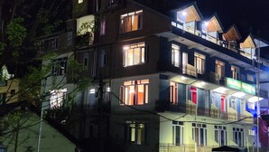 A multi-story building with illuminated windows and balconies, suggesting a hotel or residential complex. - CS Shhandella Hotel (Manali)