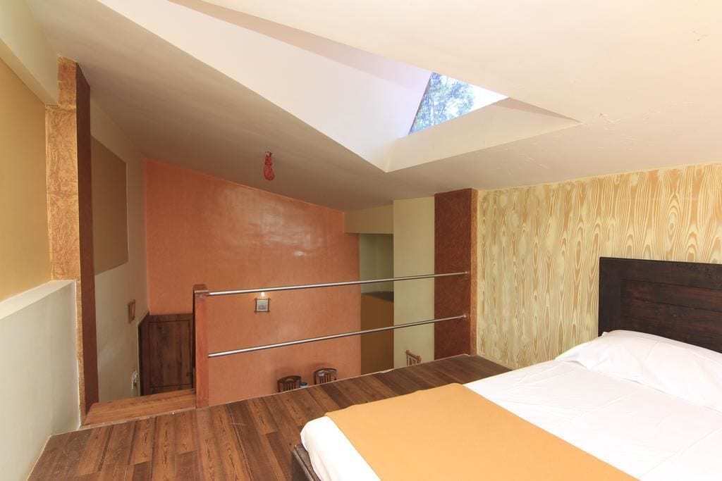 A bedroom with a skylight, wooden flooring, a bed with white bedding, and a wooden headboard.