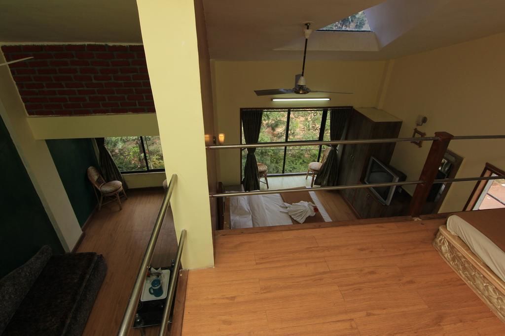 Habitación con piso de madera, una cama, ventilador de techo y vistas al exterior a través de una ventana.