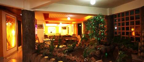 Un vestíbulo con mostrador de recepción de madera, un árbol de Navidad y una zona de estar con mesas y sillas.