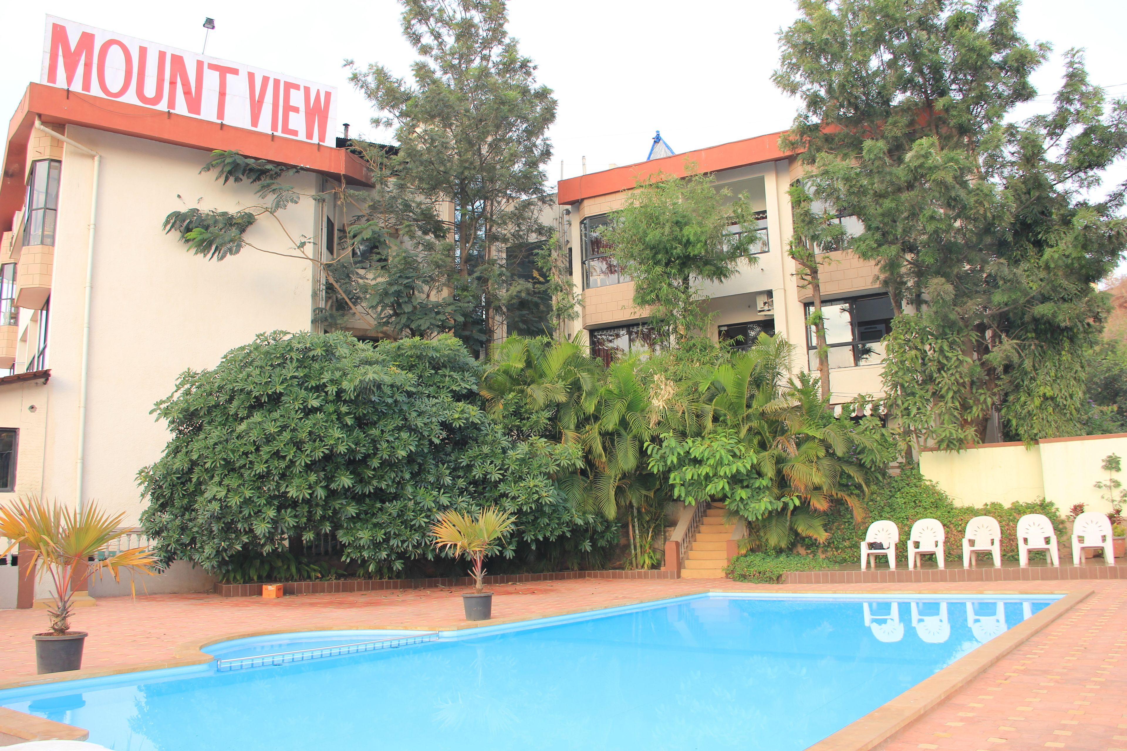 A hotel named Mount View with a swimming pool, surrounded by lush greenery and a staircase leading to the entrance.
